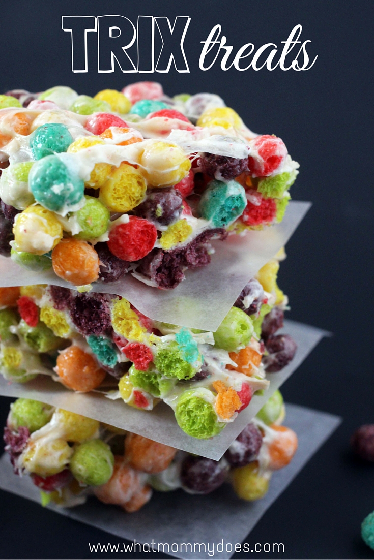 A stack of rice Krispy style treats made with colorful trix cereal. Each layer is separated by parchment paper for summer bake sale ideas.