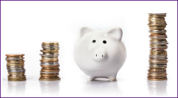stack of coins next to a white piggy bank