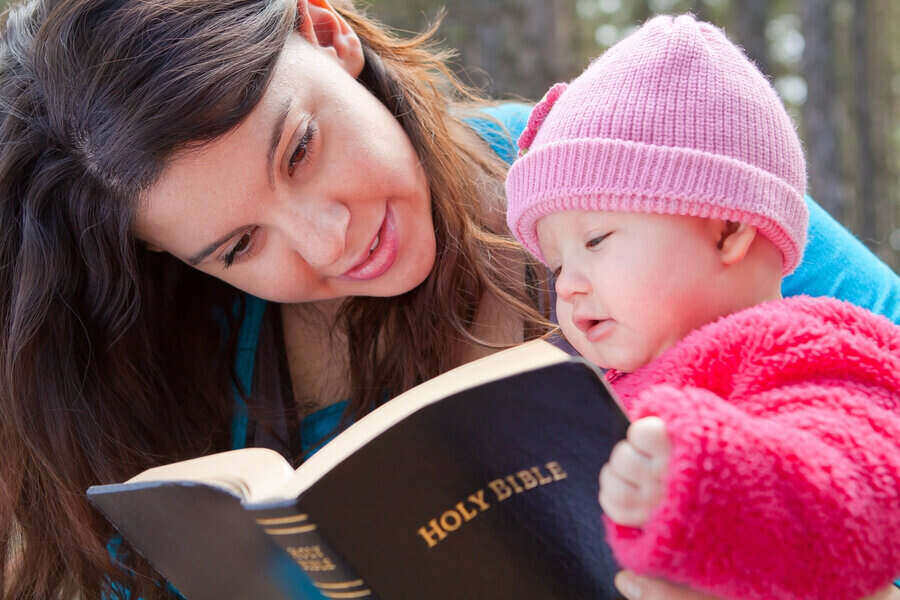 Mom And Baby Daughter Reading Bible outdoors