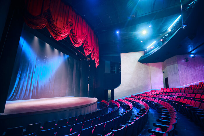 an empty theater with red seats and a red curtain 