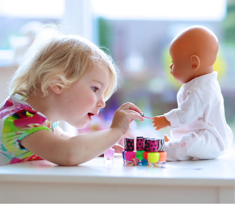 Little girl painting a doll to make money