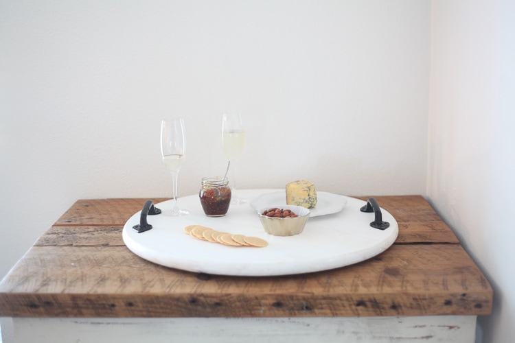 Large white serving tray with black handles. With wine glasses and snacks on tope of it.