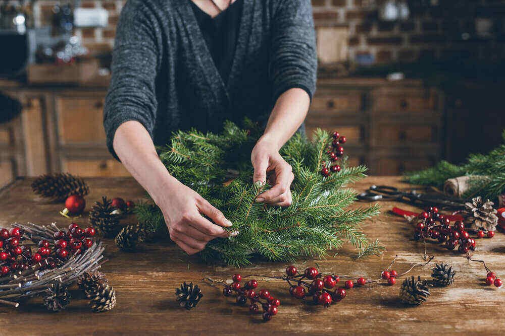 A christmas wreath being made on a table out of pine branches.