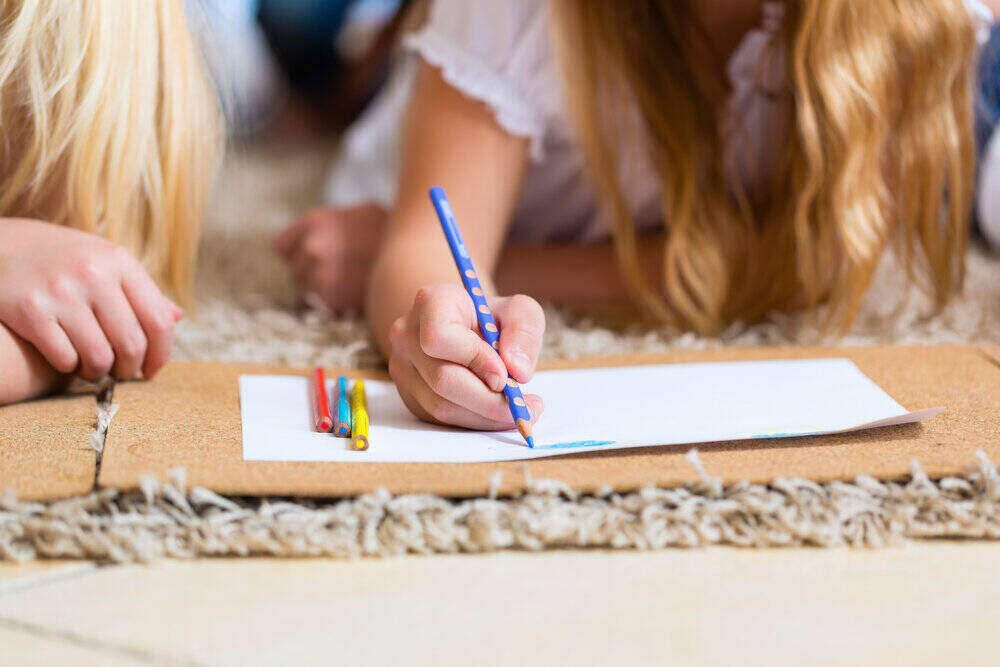 Family, mother, father and daughters are at home, the children coloring on the floor.