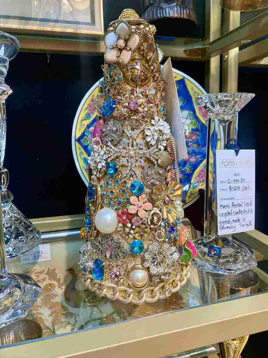 A Brooch tree made from old jewelry that has been thrifted and decorated around a foam tree core.