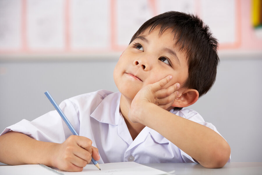 young asian child looking up in the air while hold a pencil over paper