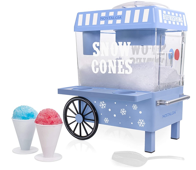 A light blue snow cone maker resembling a small cart labeled "Nostalgia Snow Cones," with "Refreshing" written on the top. It has faux wheels, snowflake decorations, and comes with two snow cones (one blue, one red) and a white scooper—an easy choice for School Market Day Ideas to make and sell.