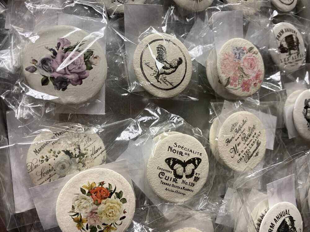 Round magnets individually wrapped, featuring vintage-style designs with flowers, birds, and butterflies. Each has unique text and artwork on its surface, crafting a charming old-fashioned aesthetic. These are among the hottest crafts to make and sell for those appreciating timeless elegance.