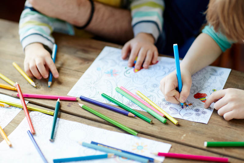Close-up of children coloring with pencils together