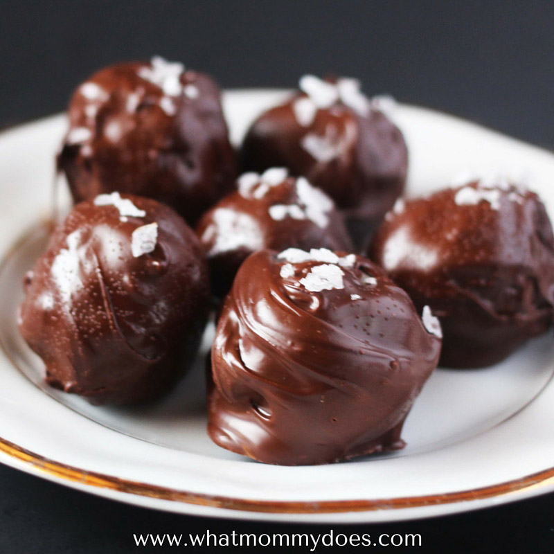 a plate of glossy chocolate truffles with sea salt sprinkled on top 