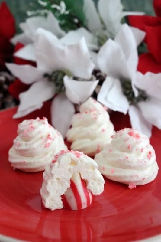 small whipped meringue cookies with a red and white striped Hershey kiss inside