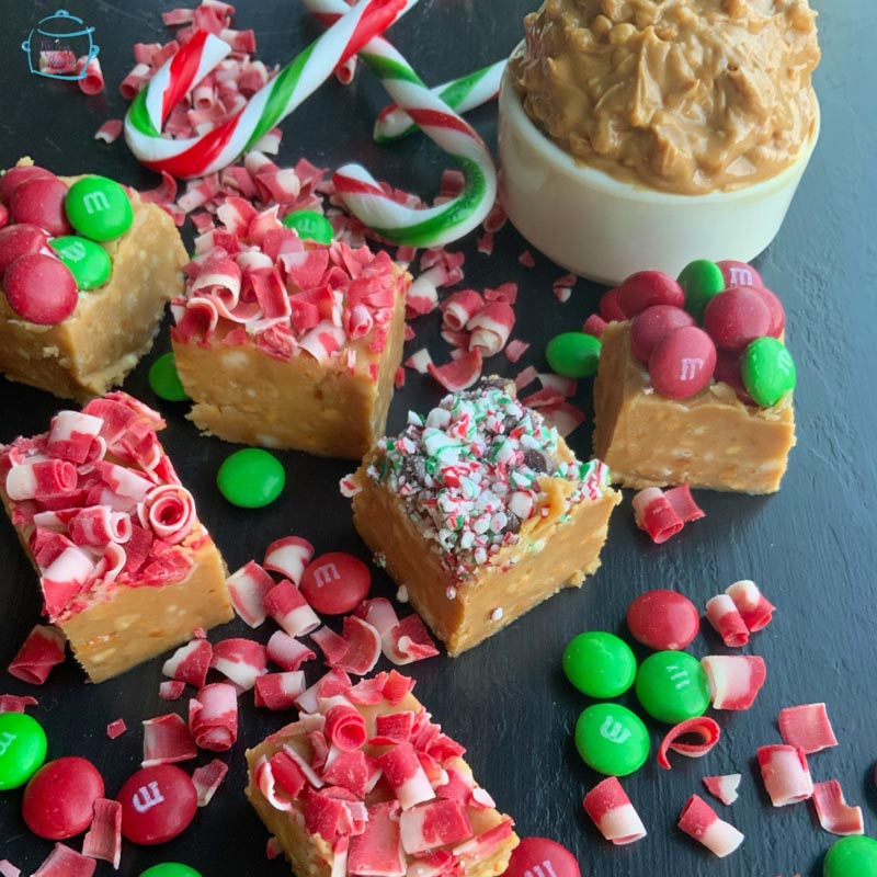 several pieces of peanut butter fudge with festive sprinkles and candy scattered around
