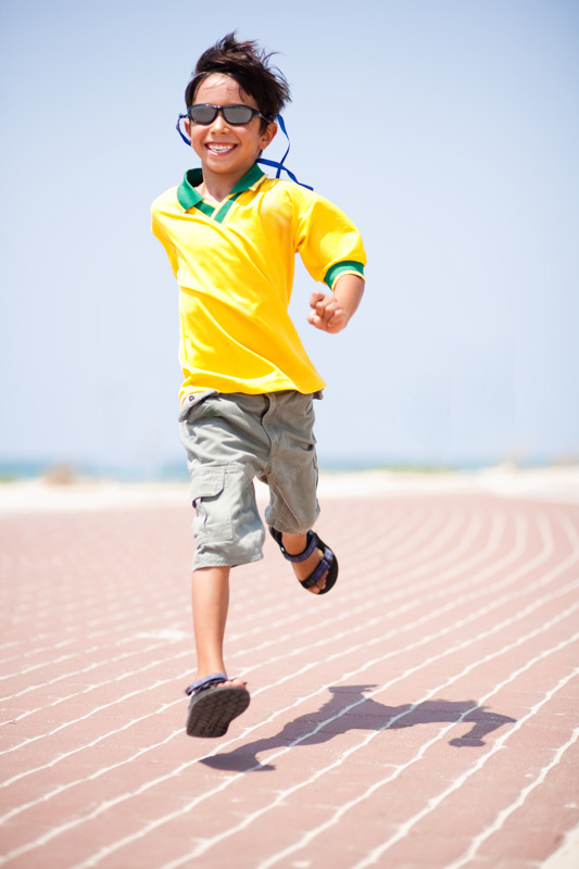Young kid running on race track and enjoying himself