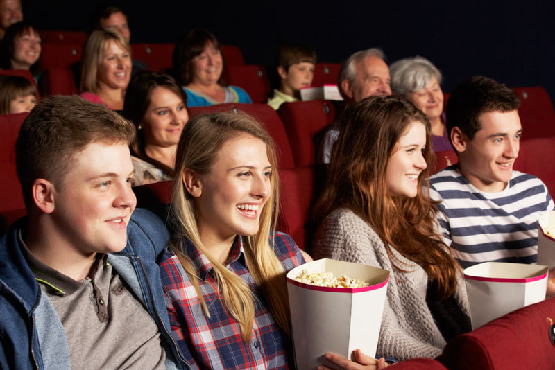 group of teenage friends watching a movie at the theatre