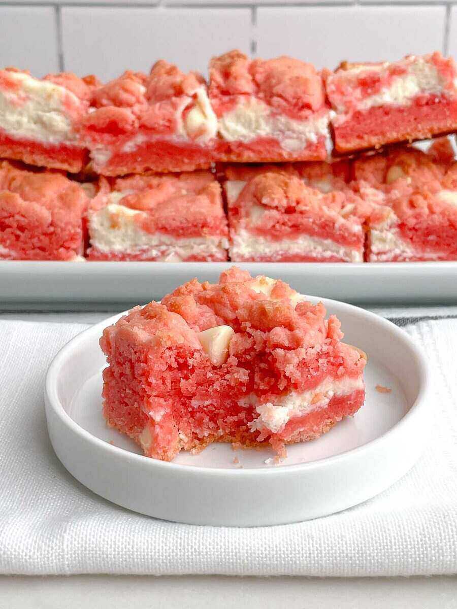 strawberry brownie squares behind a white plate that holds only one of them