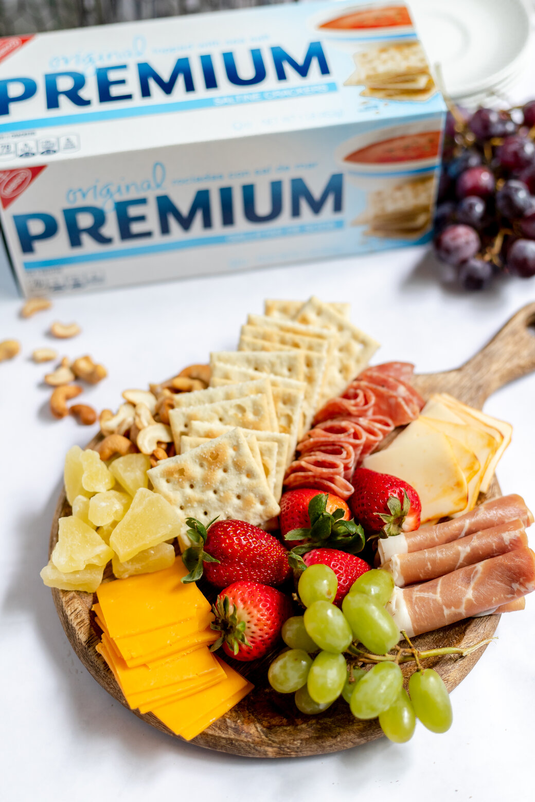 simple summer snack board with seasonal fruit, premium crackers, meat and cheese