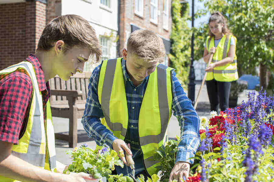 Group Of Helpful Teenagers Planting And Tidying Communal Flower
