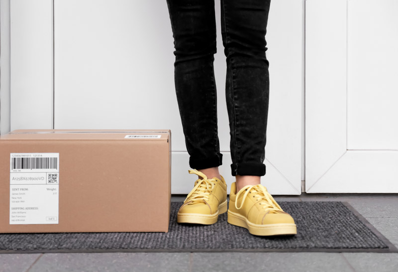 woman standing next to package at doorstep