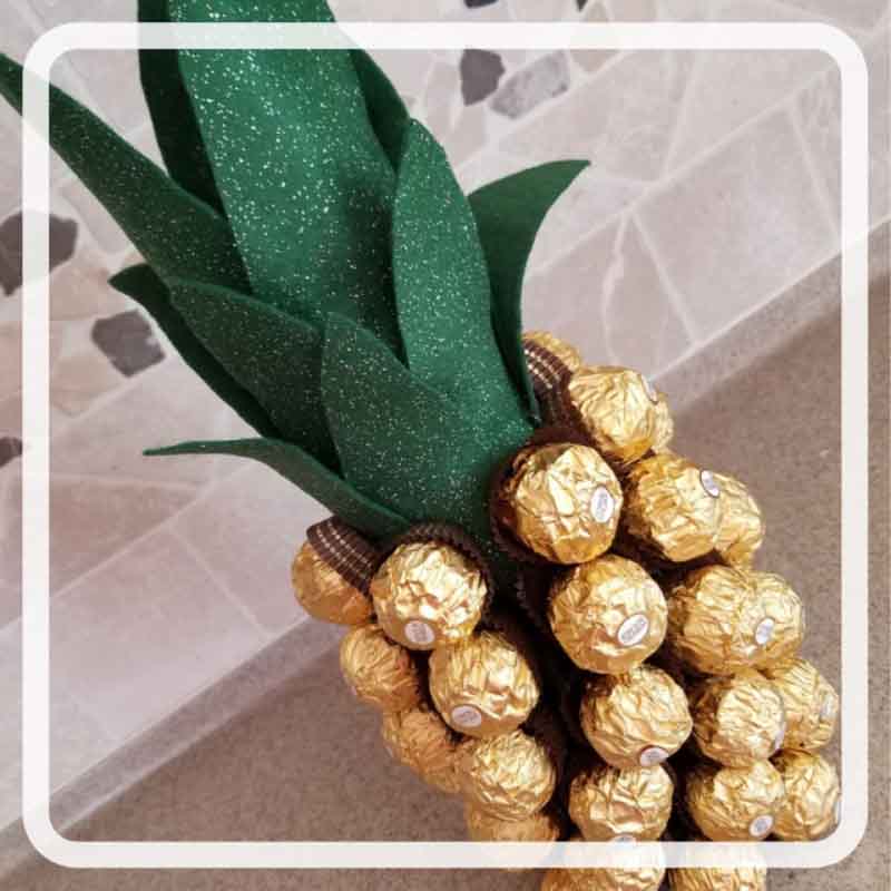 a wine bottle used as a base for a craft using ferrero rocher chocolates to make a DIY pineapple