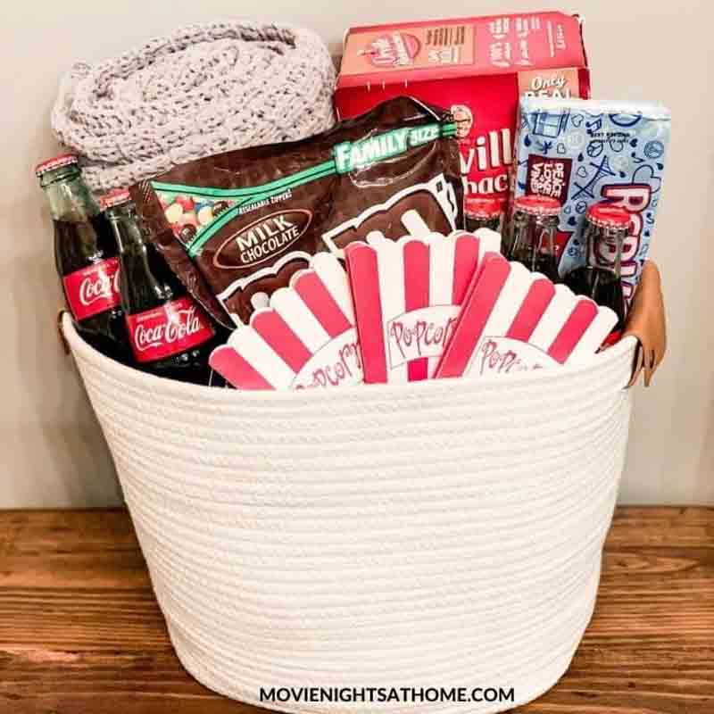 woven basket filled with popcorn, candy and a blanket for movie night gift