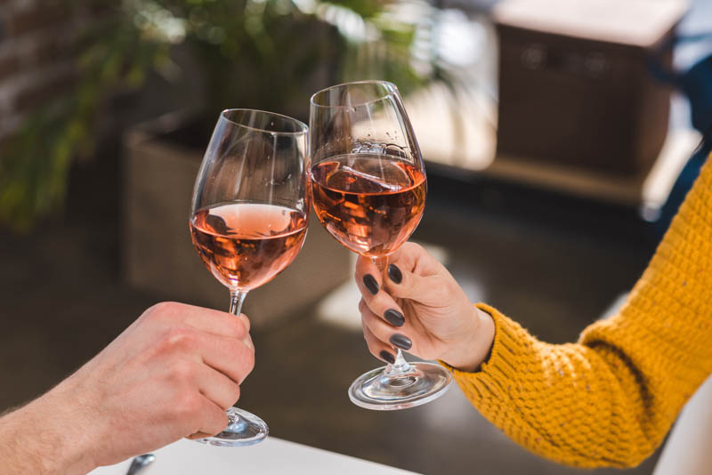 two people doing cheers with glasses on wine