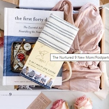 A gift box designed for new or postpartum mothers contains a soft pink robe, a book titled "The First Forty Days," a 3-in-1 multi-use cover, and a striped cloth item. Perfect for Christmas gifts, it includes thoughtful items to provide comfort and care for new parents.