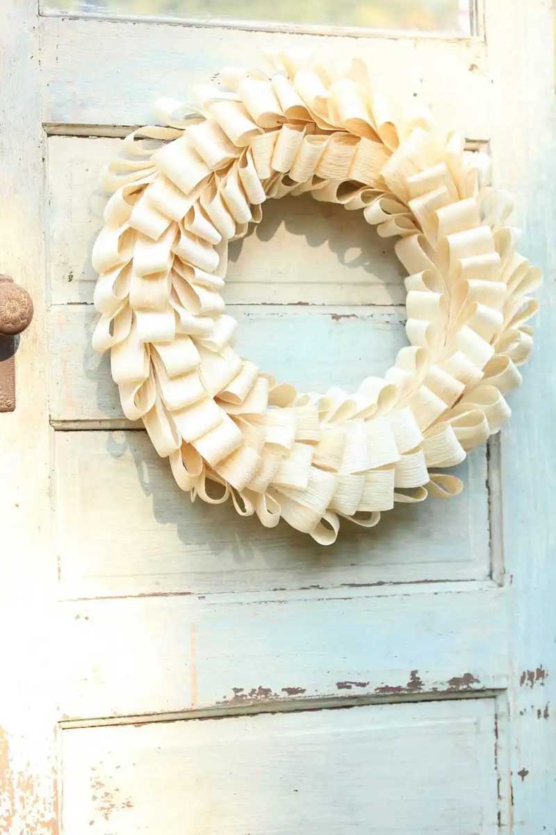 simple cream colored corn husk wreath on an old wood door