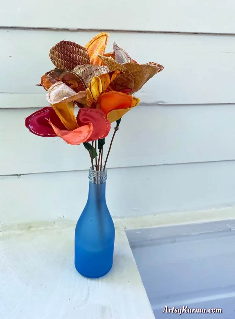 DIY fall fabric flower crafts to sell displayed in a blue bottle