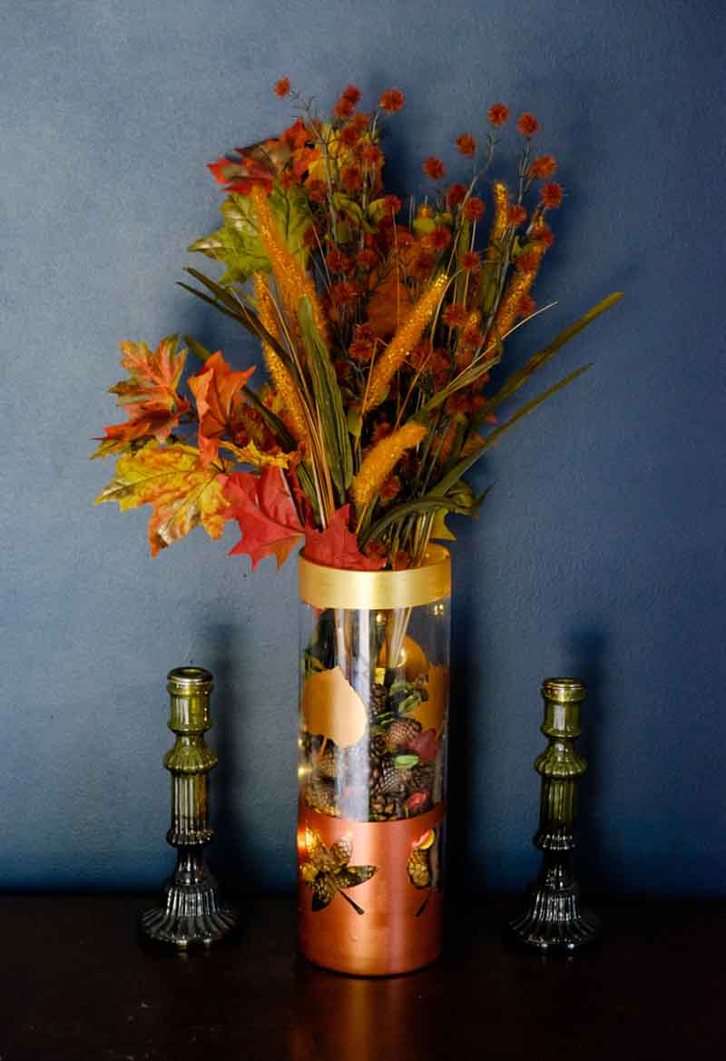 tall glass vase with metallic leaf cutouts, filled with florals