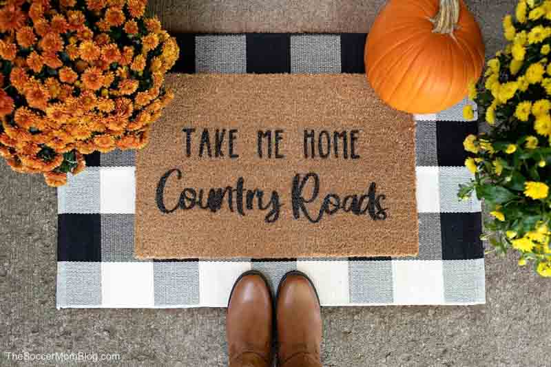 customizable stenciled fall door mat crafts to sell - bird's eye view of doormat that reads "Take Me Home Country Roads"