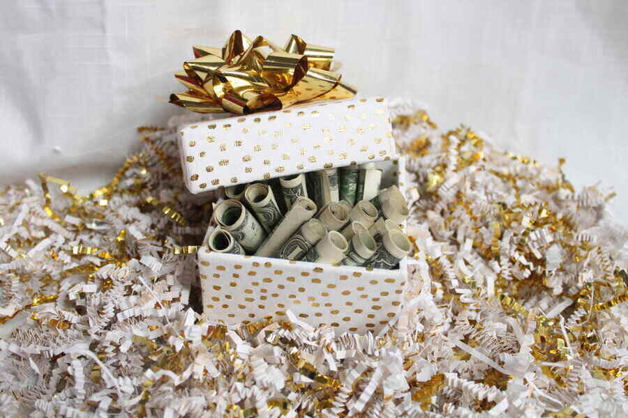 white with gold polka dots gift box full of money with a gold bow on top