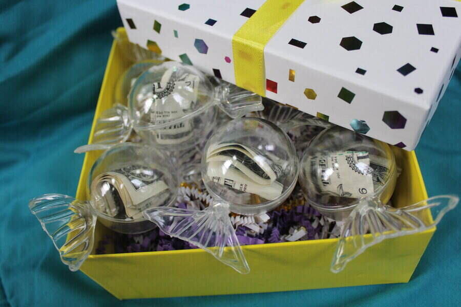 clear candy shaped containers holding money in a colorful gift box