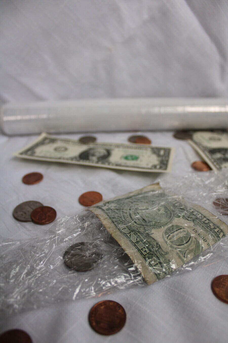 plastic wrap with dollar bills and coins wrapped in it