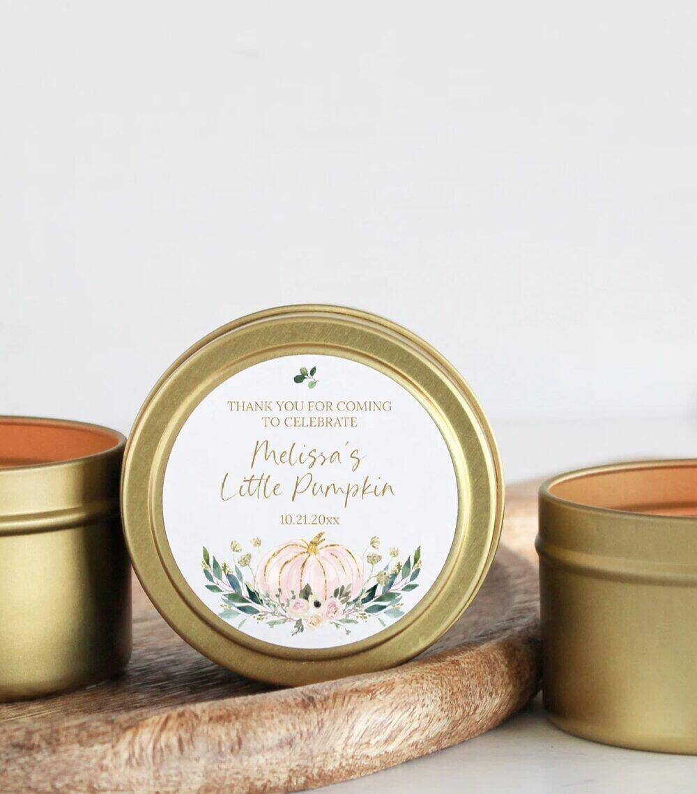 A photo of a gold metal container with a sticker making the candle into a baby shower favor. 