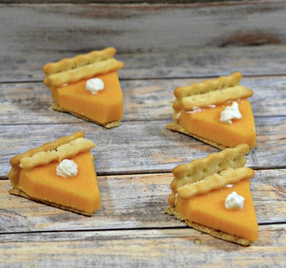 A wooden table with what appears to be tiny slices of pumpkin pie that are actually cheese and crackers. 