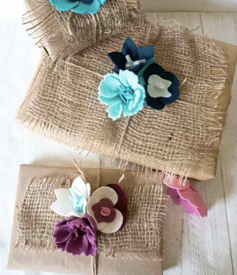 A photo of a white tabletop with Burlap and felt flower gift wrapping