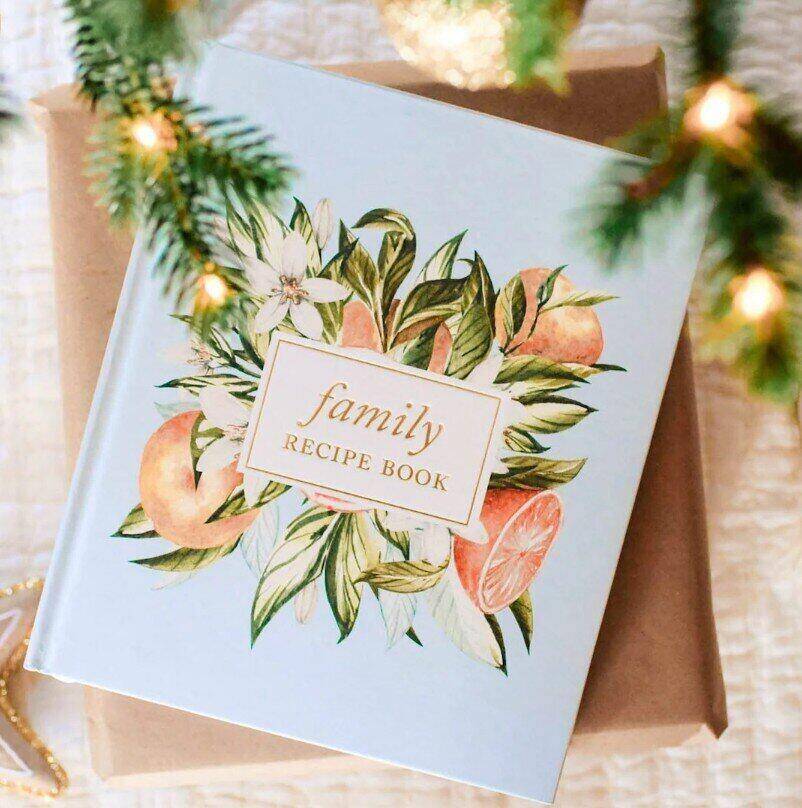 mockup image of a Family Recipe Book laying underneath a lit Christmas tree branch