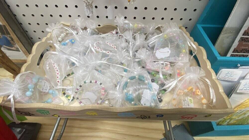 Small clear mesh baggies with bracelets in them in a display box on a shelf at a craft booth.