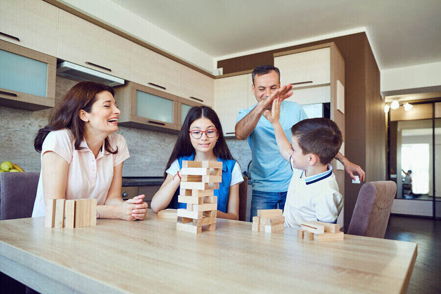 A cheerful family plays board games at home in the kitchen