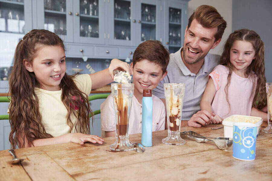 Father Making Ice Cream Sundaes With Children At Home