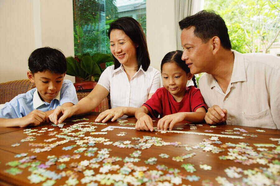 a family of 4 working a puzzle on a table.