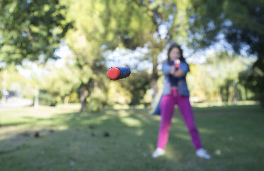 9 year old little girl shooting with toy pistol. Flying darts on focus