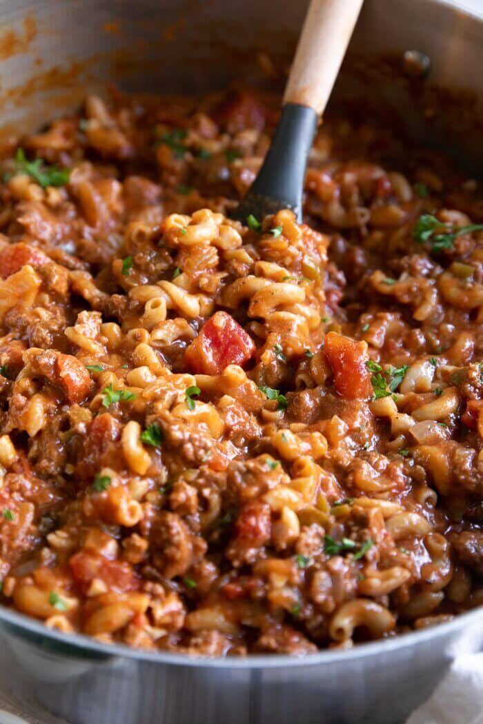 A spoon holding up meaty, vegetable filled goulash. 
