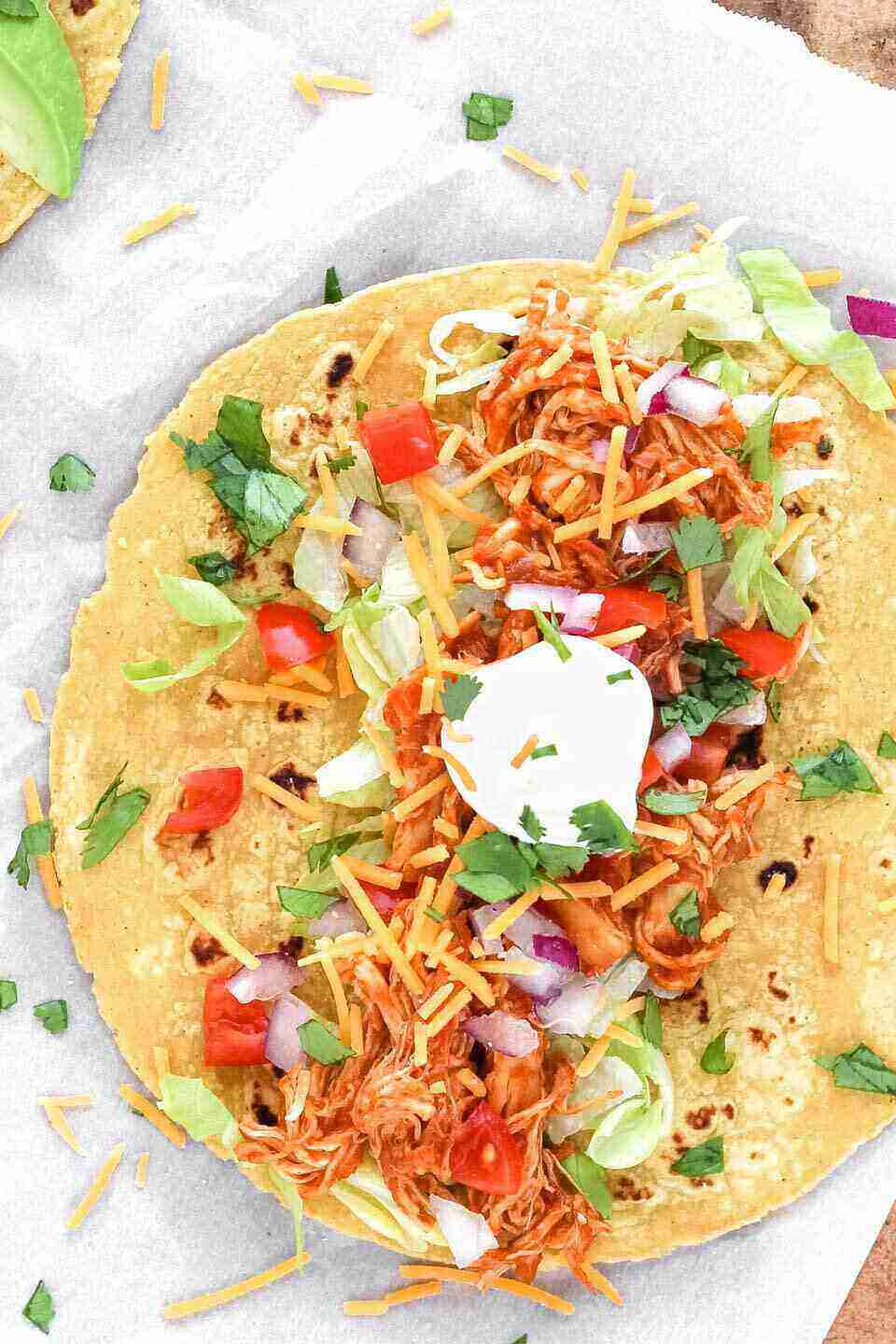 A corn tortilla with chicken, cilantro, tomatoes and a dollop of sour cream. 