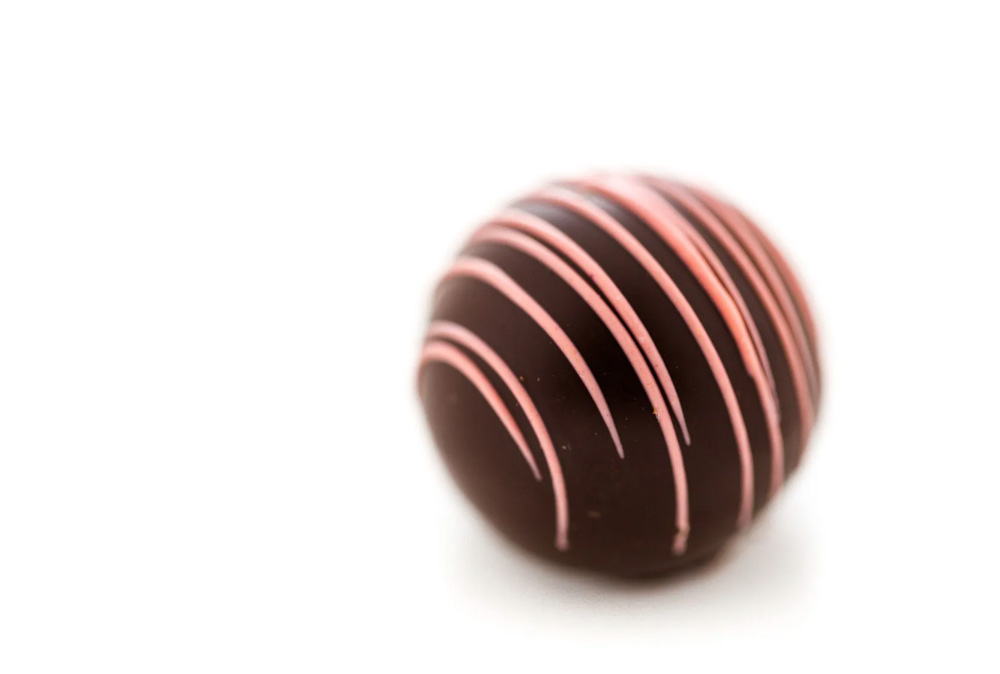 Elegant Godiva chocolate truffle with pink drizzle, a luxe treat for baby shower dessert tables.