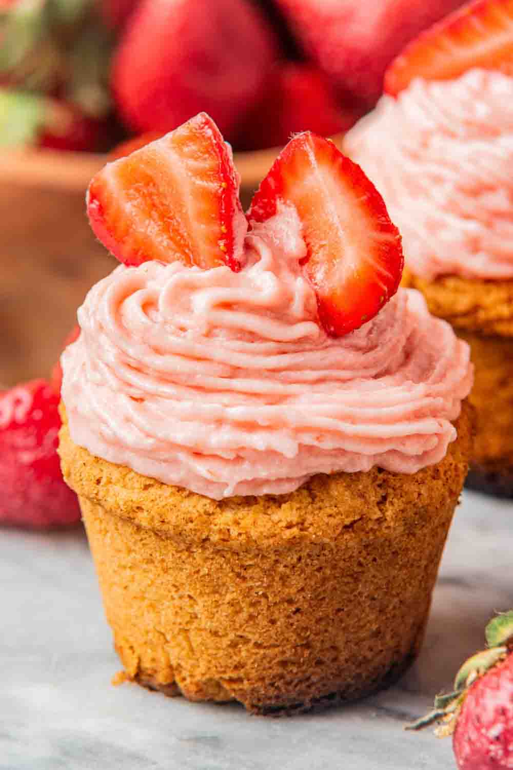 Strawberry cupcakes with pink cream cheese frosting and fresh strawberry slices.