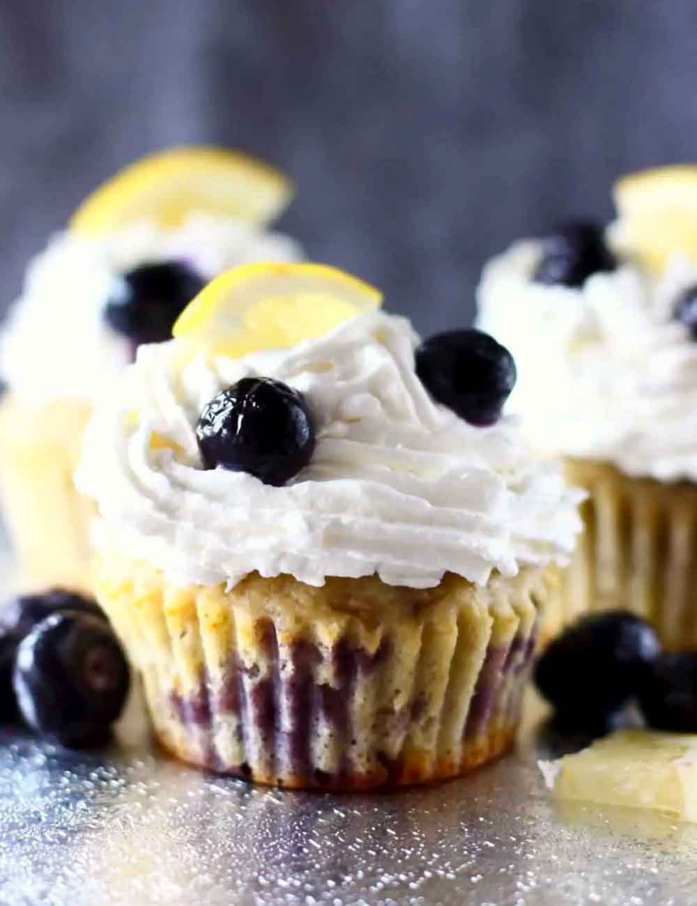 Lemon blueberry cupcakes topped with whipped frosting, blueberries, and lemon slices, perfect for DIY baby shower desserts.
