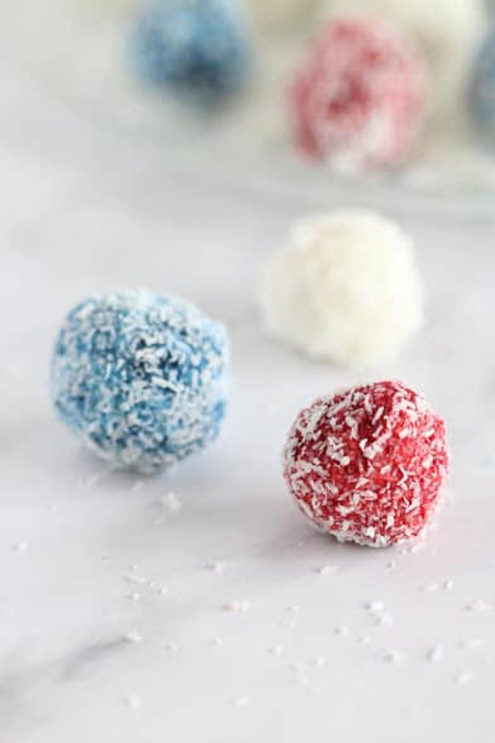 Red, white, and blue coconut balls coated in shredded coconut, a colorful baby shower dessert idea.