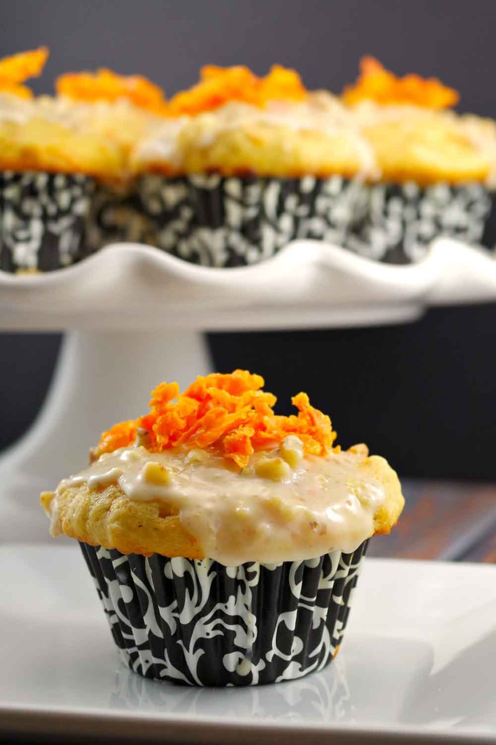 Carrot cake muffins with glaze and shredded carrot topping, a unique twist on homemade baby shower desserts.
