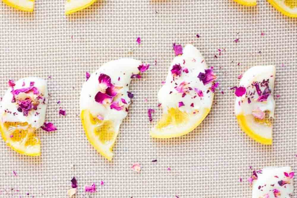 Lemon slices dipped in white chocolate and sprinkled with dried rose petals, elegant DIY baby shower desserts.